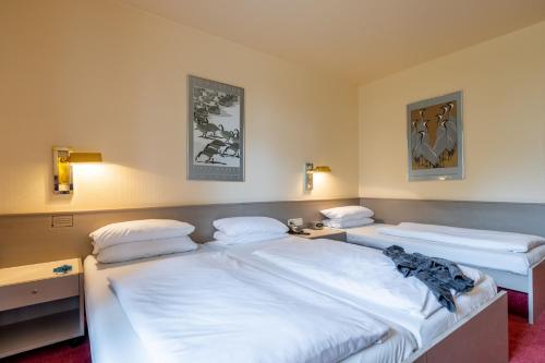 two twin beds in a room with two lamps at Hotel Baden-Baden in Baden-Baden