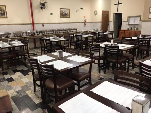 a dining room with tables and chairs and a cross on the wall at Hotel Benfica in Aparecida