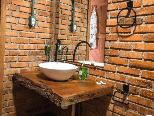 a bathroom with a sink on a brick wall at Pousada Café da Mata in Alto Caparao