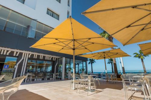 a patio with tables and chairs and umbrellas at Hotel Omeya in Martil