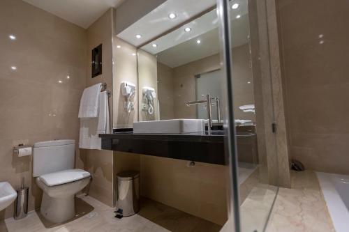 a bathroom with a sink and a toilet and a mirror at Suites Hotel Omeya in Martil