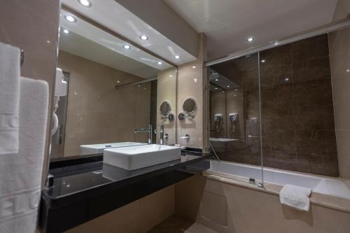 y baño con lavabo y ducha con espejo. en Suites Hotel Omeya en Martil