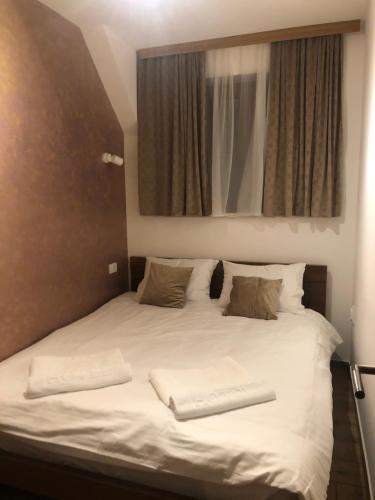a large white bed with two pillows and a mirror at Apartmani Vidatela Kopaonik in Kopaonik