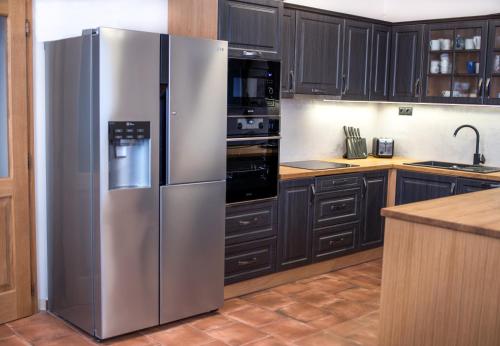 a stainless steel refrigerator in a kitchen with black cabinets at Draslovanka in Bedřichov