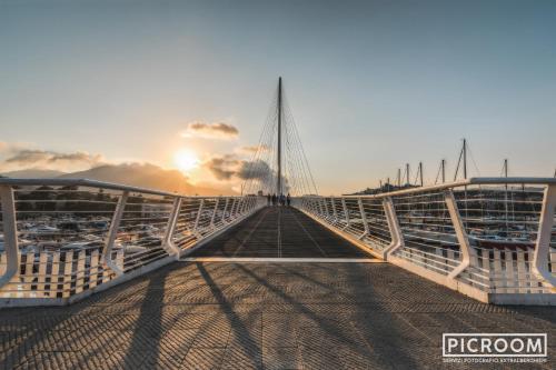 a bridge over the water with the sun in the background at 5 terre dei poeti in La Spezia
