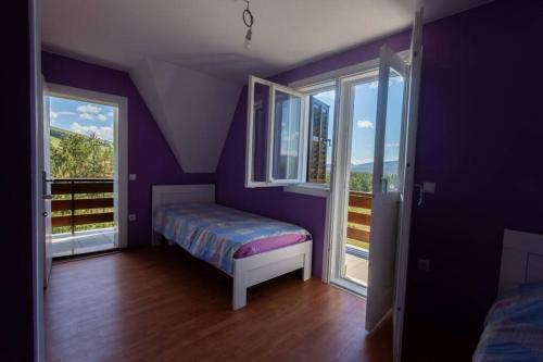a purple bedroom with a bed and two windows at Mesto za odmor in Zlatibor