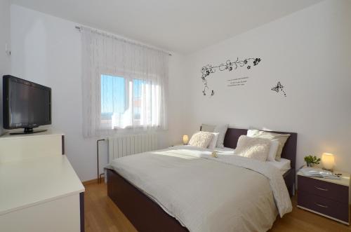 1 dormitorio blanco con 1 cama y TV en Apartmani Adela en Solin