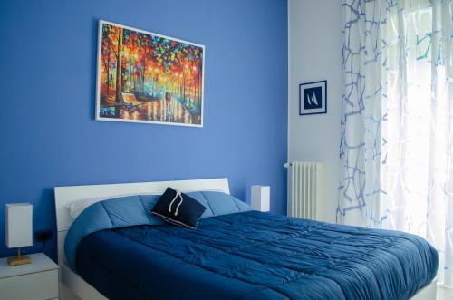 a blue bedroom with a bed and a painting on the wall at Primopiano Holiday House in Salerno