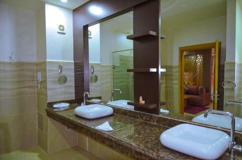 a bathroom with two sinks and a large mirror at Hotel SAHARATEL in Laayoune