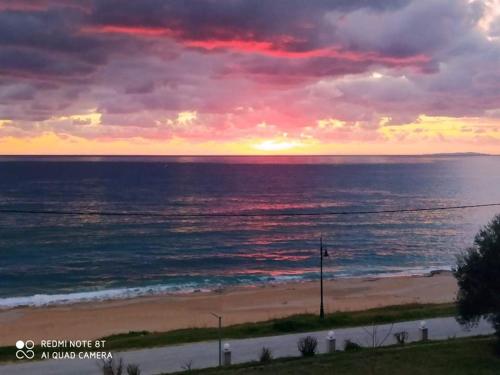 a sunset over a beach with the ocean at Akrothalassia in Ligia
