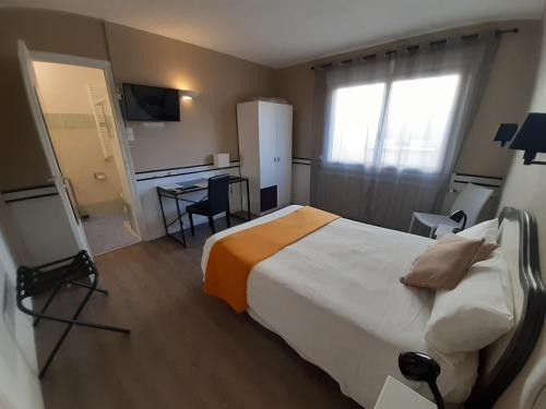 une chambre d'hôtel avec un lit et un bureau dans l'établissement Hôtel du Tricastin, à Pierrelatte