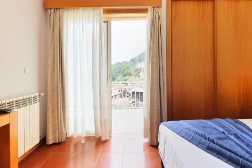 a bedroom with a bed and a large window at Aparthotel Gerês in Geres