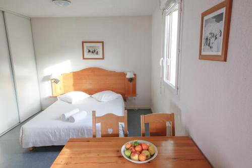 a room with a bed and a bowl of fruit on a table at Résidence Plein Soleil in Avrieux