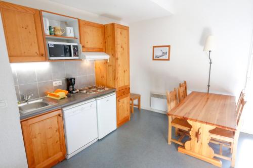a kitchen with wooden cabinets and a wooden table at Résidence Plein Soleil in Avrieux