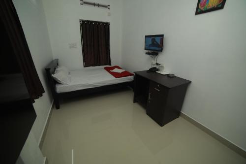 a small room with a small bed and a desk at MEGHNA RESIDENCY in Trivandrum