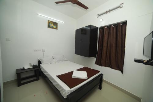 a small bedroom with a bed and a tv at MEGHNA RESIDENCY in Trivandrum