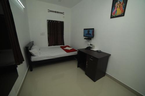 a small bedroom with a small bed and a desk at MEGHNA RESIDENCY in Trivandrum