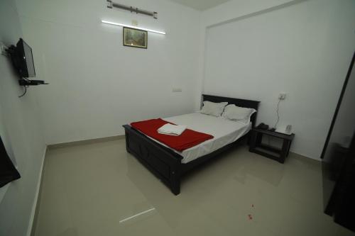 a bedroom with a bed with a red blanket at MEGHNA RESIDENCY in Trivandrum