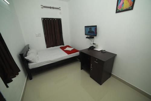a small bedroom with a small bed and a desk at MEGHNA RESIDENCY in Trivandrum