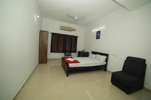 a bedroom with a bed and a chair in it at MEGHNA RESIDENCY in Trivandrum