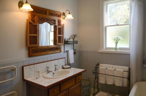 een badkamer met een wastafel, een spiegel en een raam bij The Saddlery in Greytown