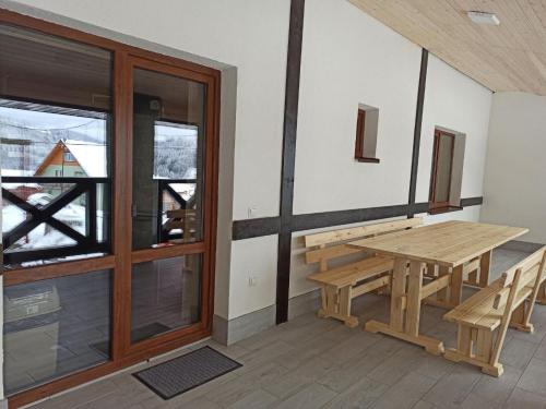 una panca in legno e un tavolo sul balcone di New 2020 specious cottage DRUZI a Bukovel