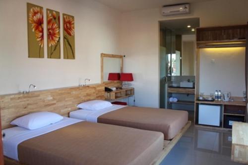 a hotel room with two beds and a television at Hotel Karthi Kuta in Kuta