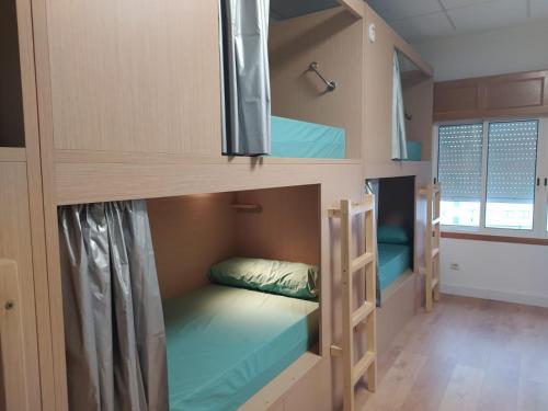 a room with three bunk beds in it at Albergue Río Eume in Puentedeume