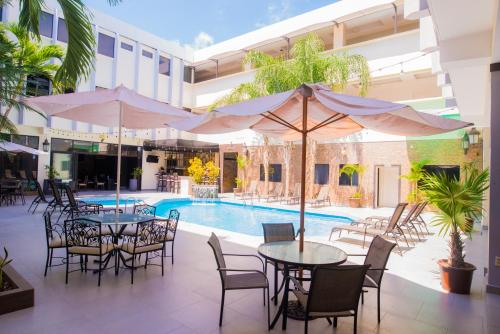 um pátio exterior com mesas e cadeiras e uma piscina em Hotel Presidente Beach Salinas em Salinas
