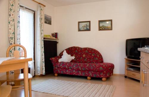 een woonkamer met een rode stoel en een tv bij Haus Steinbrecher in Anger