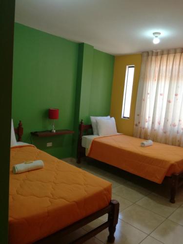 two beds in a room with green walls at Sunset Hostel Airport in Lima