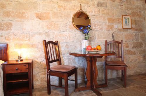 a table with two chairs and a mirror on a stone wall at Agrovino Lofou in Lofou