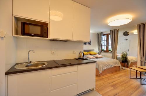 a kitchen with a sink and a room with a bed at Apartament Królewski in Karpacz