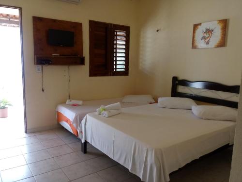 a bedroom with two beds and a tv on the wall at Pousada Meu Paraíso in Lagoinha