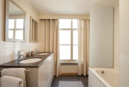 een badkamer met een wastafel, een spiegel en een bad bij Skindles Guesthouse in Poperinge