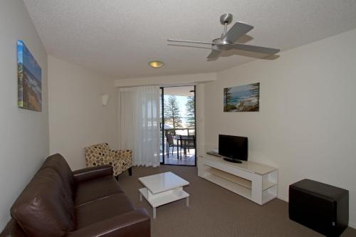 a living room with a couch and a television at The Beach Retreat Coolum in Coolum Beach