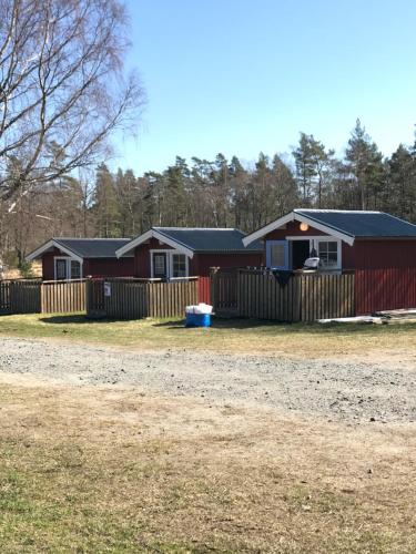 eine Reihe von Häusern mit einem Zaun und einem Hof in der Unterkunft Björsjöås Vildmark - Small camping cabin close to nature in Olofstorp