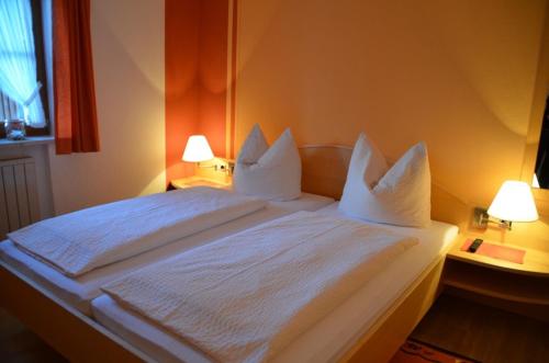 a large white bed in a room with two lamps at Haus Tschakert in Anger