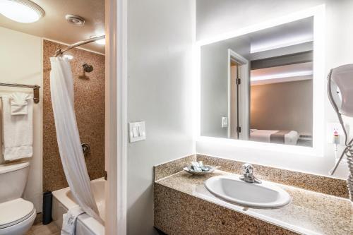 a bathroom with a sink and a toilet and a mirror at Inn at 50 Long Beach Convention Center in Long Beach