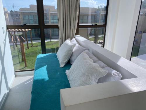 a couch with pillows on it in front of a window at Morada do Toque - TOQUINHA in São Miguel dos Milagres