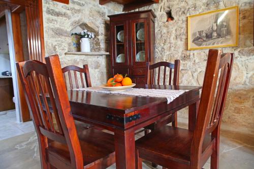 a wooden table with chairs and a bowl of oranges on it at Agrovino Lofou in Lofou