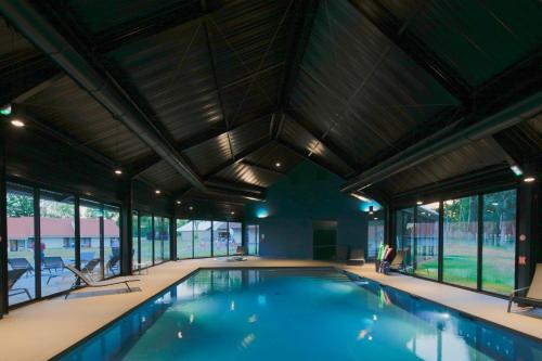 a swimming pool in a building with windows at Hôtel Lac d'Orient in Mesnil-Saint-Père
