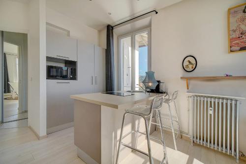 uma cozinha com um balcão e dois bancos em IMMOGROOM - Bourgeois building - Quiet - Parking - Sea view em Cannes