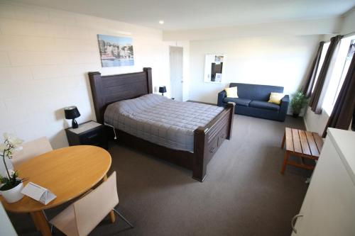 a bedroom with a bed and a table and a couch at Foreshore Motor Lodge in Lower Hutt