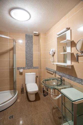 a bathroom with a toilet and a glass sink at Apartman EROS in Vrnjačka Banja