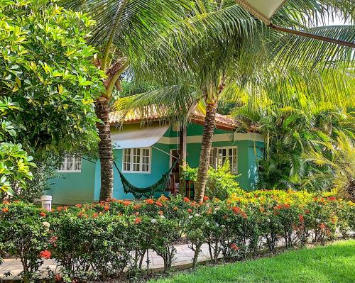 una casa verde con palmeras y flores delante de ella en La Dolce Vita Flat & Pousada, en Praia do Frances