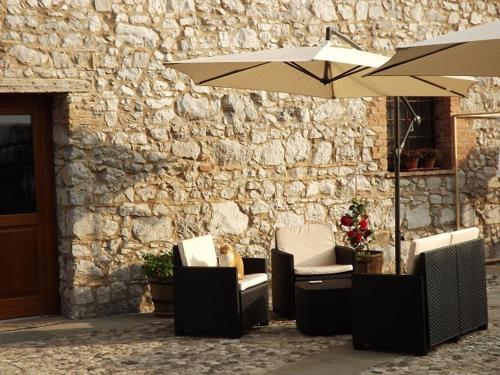 two chairs and an umbrella next to a stone wall at Casa della Fornace in San Vito al Torre
