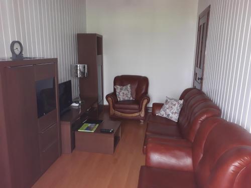 a living room with a leather couch and two chairs at Casa da Tia Marina in Lajes das Flores