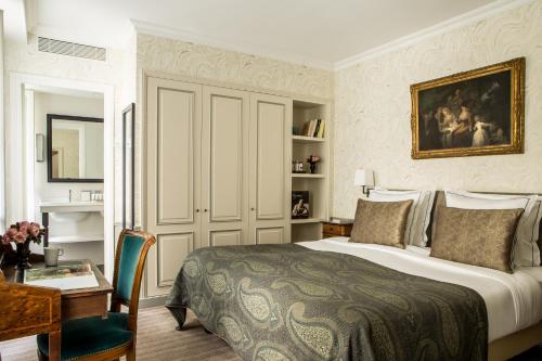 a bedroom with a large bed and a desk and a table at Hôtel des Saints Pères - Esprit de France in Paris