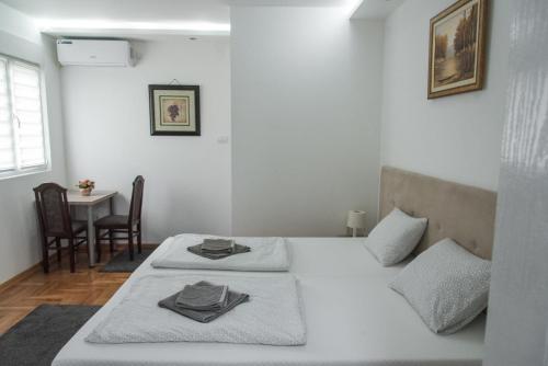 two beds in a room with a table and chairs at APARTMAN TEA in Belgrade
